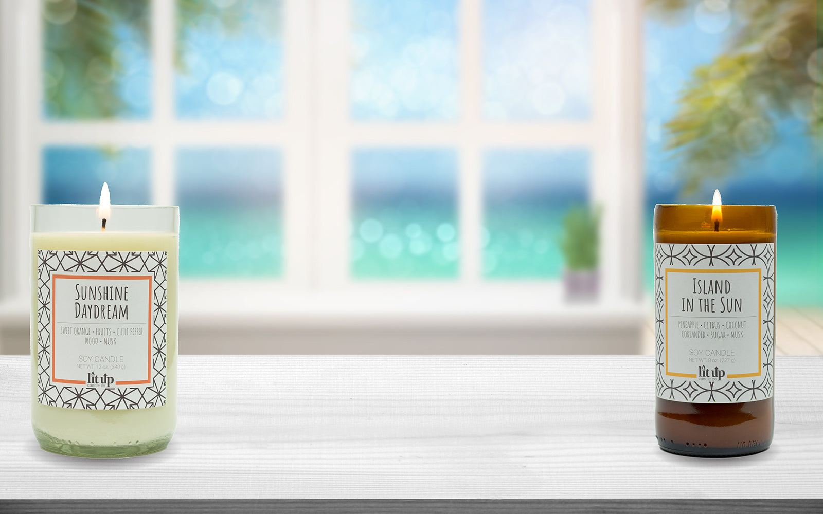 Sunshine Daydream and Island in the Sun candles burning on counter in front of window with the ocean in the background.